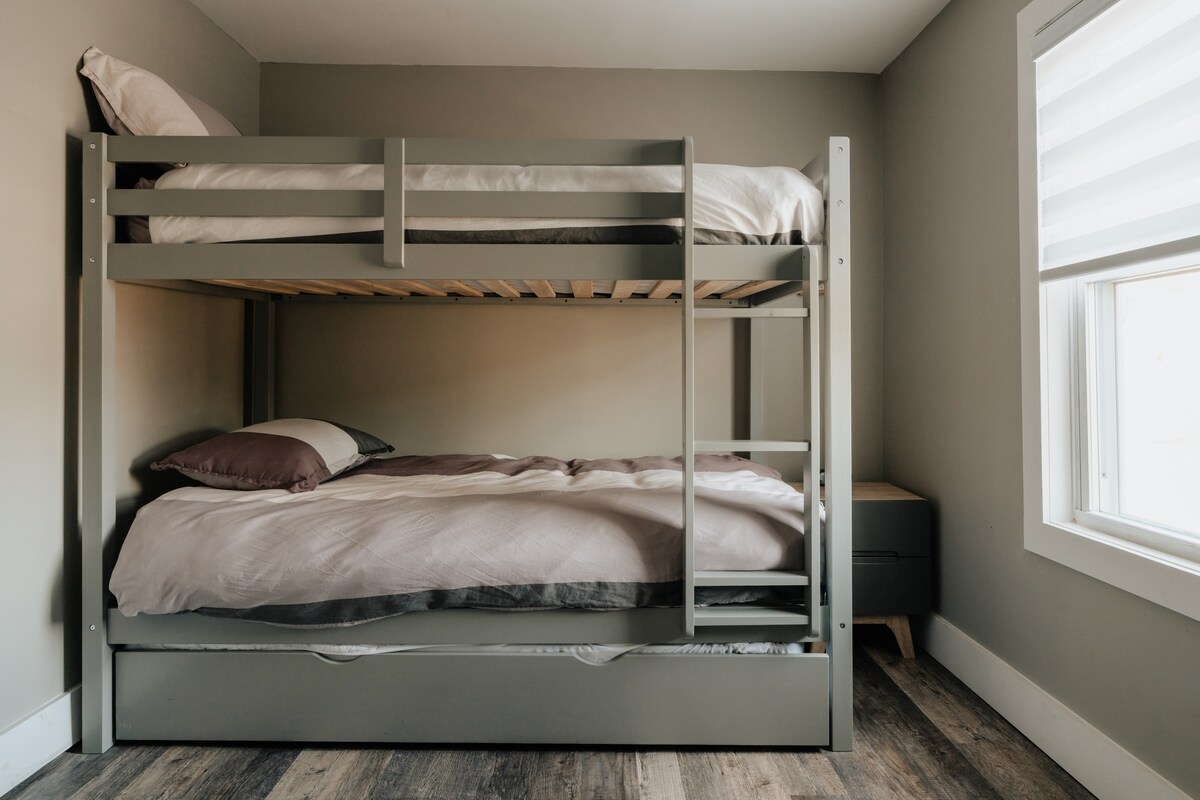 Un dormitorio acogedor con una litera con una cama nido extraíble en la litera inferior, que ofrece un amplio espacio para dormir para los huéspedes.