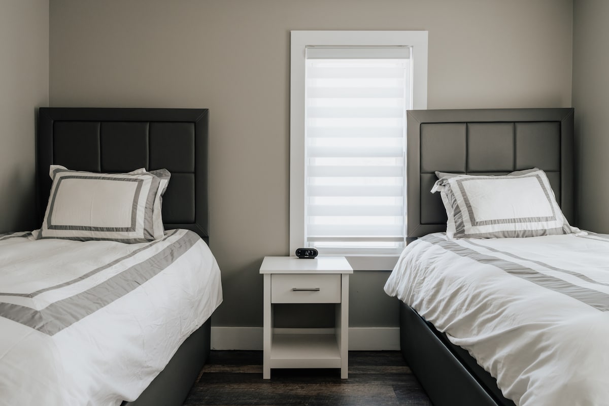 Un encantador dormitorio con dos camas individuales, una de las cuales incluye una cama nido extraíble, que proporciona arreglos flexibles para dormir.