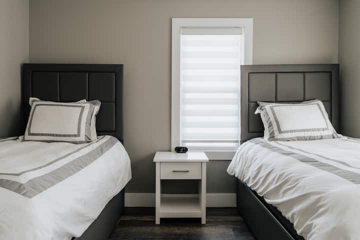 Un encantador dormitorio con dos camas individuales, una de las cuales incluye una cama nido extraíble, que proporciona arreglos flexibles para dormir.