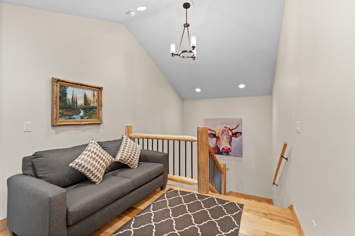 Pracovný priestor na poschodí s písacím stolom a dvojitou pohovkou na spanie. 