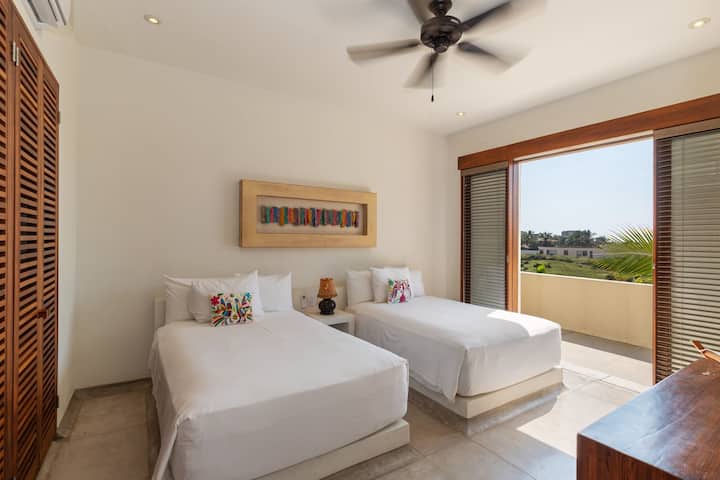 Un acogedor dormitorio doble con decoración minimalista, suave iluminación natural y acceso directo a un balcón privado con impresionantes vistas.