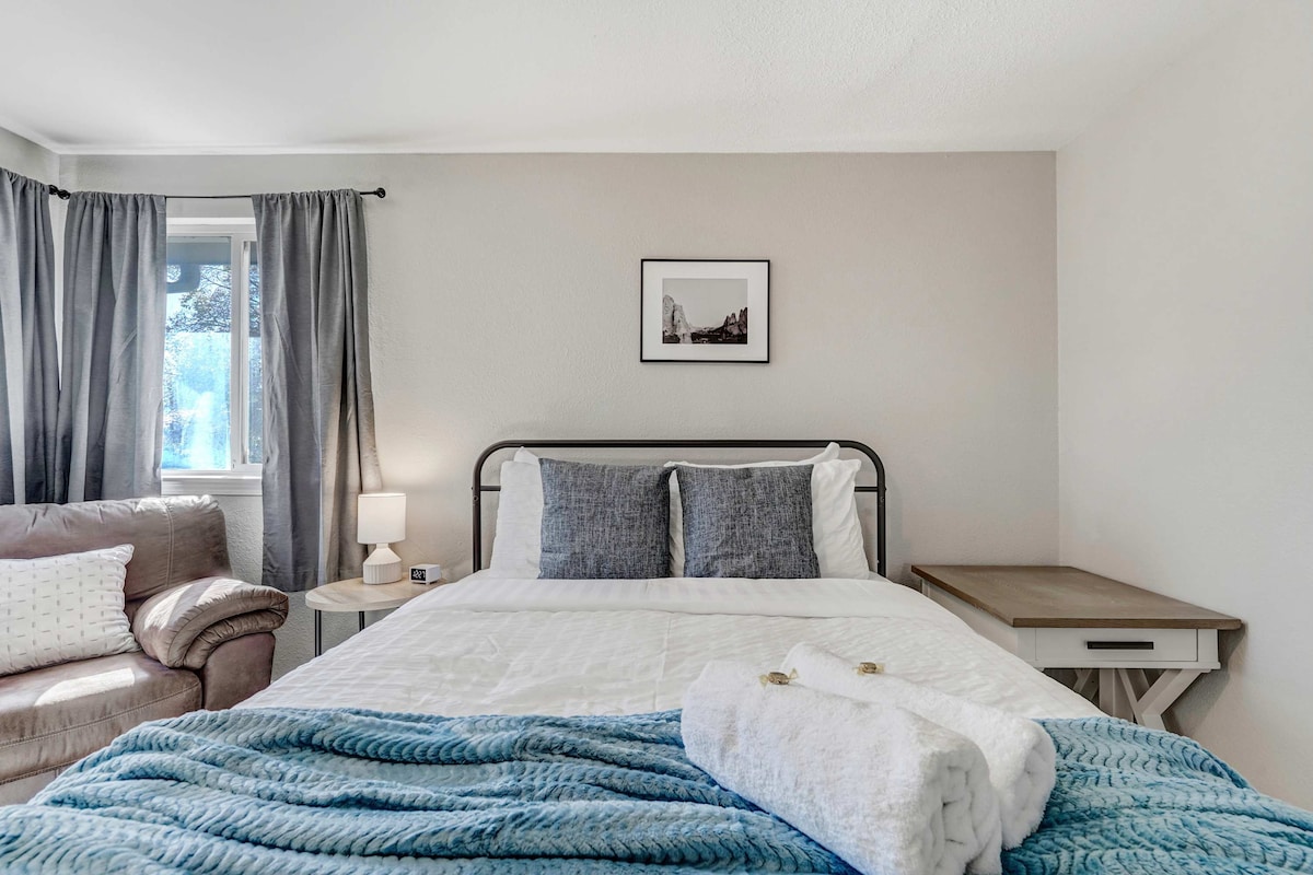 Acogedor dormitorio con rincón de lectura: relájate en esta acogedora cama tamaño queen con sábanas suaves y una silla cómoda para momentos de tranquilidad.