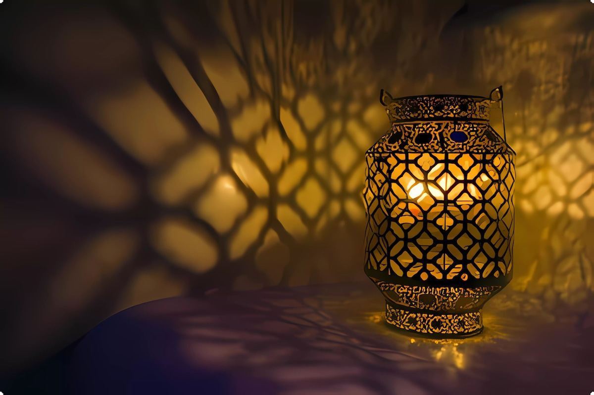 An intricately designed lantern emits a warm glow, casting detailed shadows against the wall. The cut-out patterns create a captivating interplay of light and dark, enhancing the ambiance of the space.