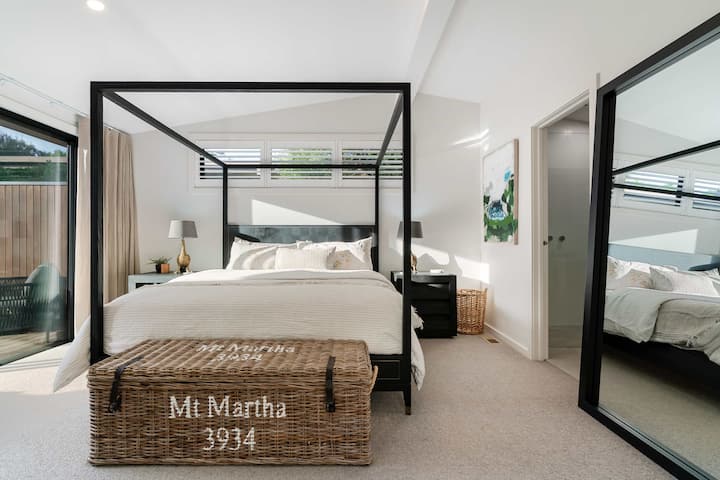Quarto principal com uma cama de dossel, suíte e portas que se abrem para o deck com banheira ao ar livre.