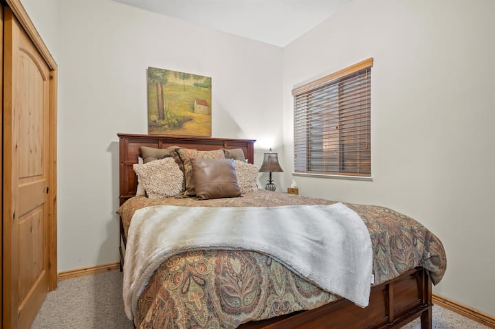 ห้องนอนห้องที่สองมีเตียงควีนไซส์ผ้าปูที่นอนหรูหราและหมอนหนานุ่ม