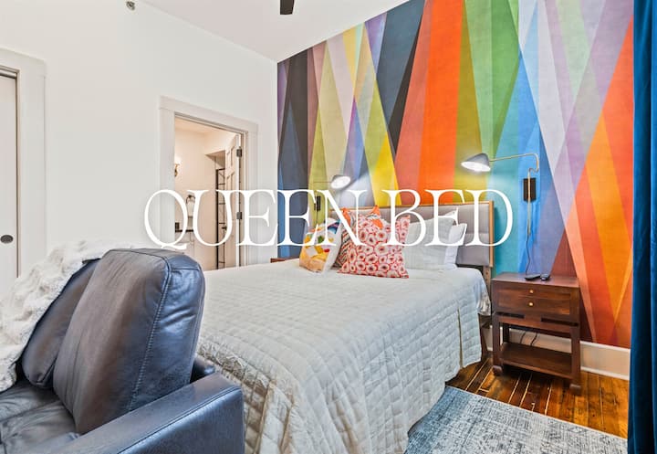 Manželská posteľ je orámovaná odvážnym stenovým umením a útulným osvetlením, čo vytvára relaxačný priestor so správnym množstvom osobnosti.