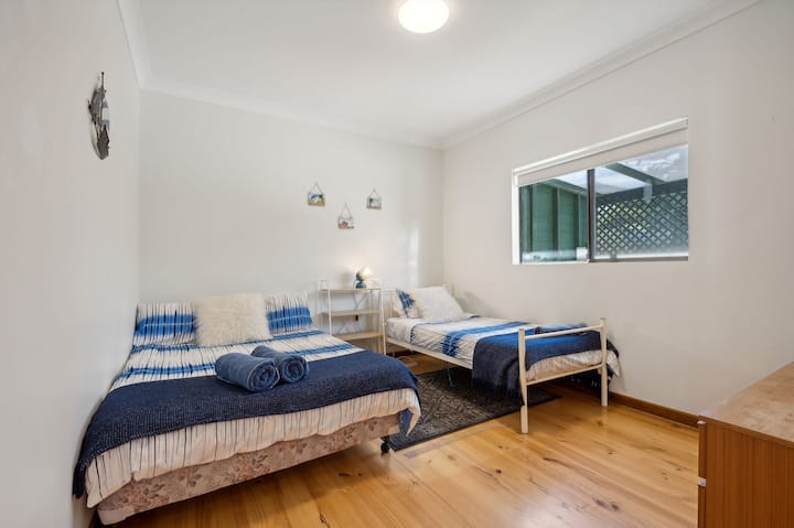 Dve jednolôžka s posteľnou bielizňou inšpirovanou námorníctvom a podlahami z lešteného dreva.