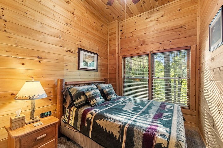 ห้องนอนใต้ดินขนาดควีนไซส์มีพัดลมเพดานโต๊ะข้างเตียงตู้เสื้อผ้าตู้เสื้อผ้าพร้อมไม้แขวนเสื้อและชั้นวางกระเป๋าเดินทาง