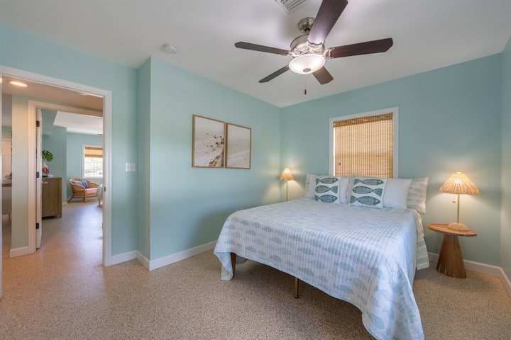 U ovoj spavaćoj sobi nalazi se udoban bračni krevet s posteljinom s motivima iz priobalja, a pored njega su dva noćna ormarića od pletenog materijala i svjetiljke u istoj boji. Stropni ventilator pruža udobnost, a ugrađena vrata ormara nude praktičan prostor za pohranu.