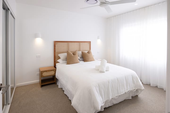 Dormitorio principal con armario, ventilador de techo y TV inteligente.