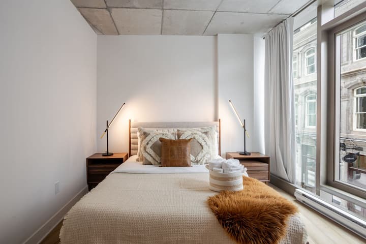 غرفة النوم رقم1 : غرفة نوم بسيطة مريحة مع نوافذ كبيرة وإضاءة ناعمة.