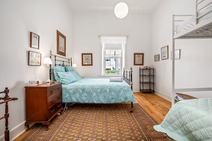 Une chambre polyvalente avec un lit double, des lits superposés et des meubles anciens adaptés aux familles.