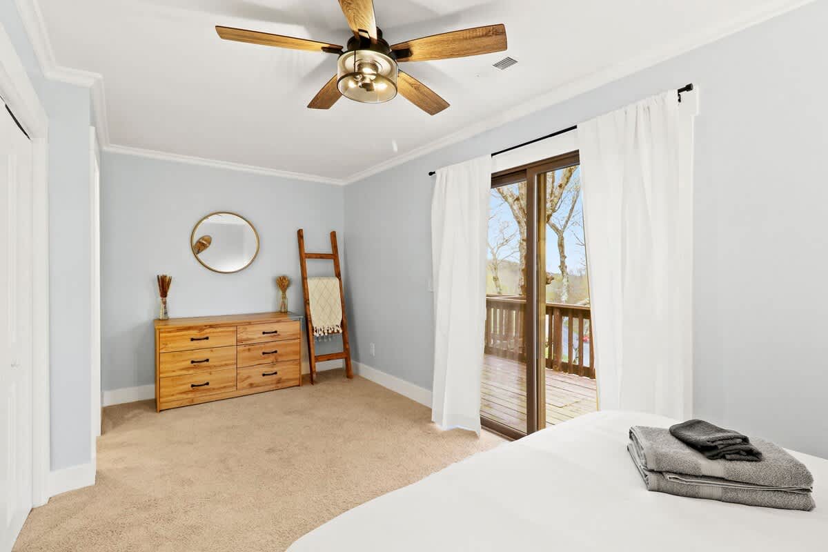 Een adem van ruimte en rust: een ruime slaapkamer versierd met minimale rustieke accenten, naadloos verbonden met het buitenleven via een glazen deur naar het balkon.