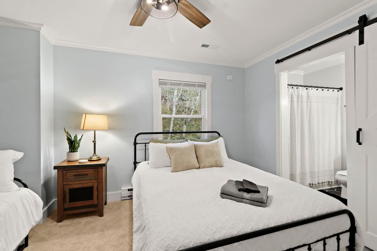 Omarm de warmte: een zacht verlichte slaapkamer versierd met lichte tinten, met een hangende schuifdeur die je uitnodigt voor een gezellig toevluchtsoord op de badkamer.