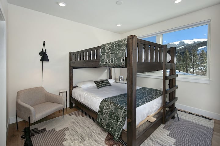 Dormitorio de invitados con literas queen sobre queen, TV inteligente y baño compartido en el pasillo.