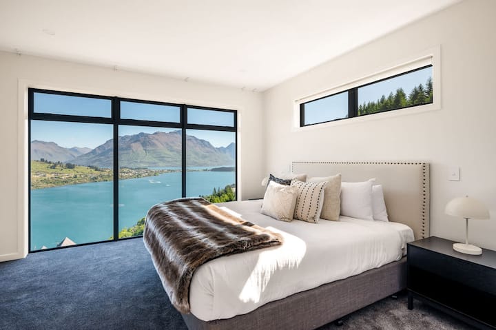 Luxusná hlavná spálňa s výhľadom – Zobuďte sa s úchvatným výhľadom na hory a jazero v priestrannom hlavnom apartmáne s plyšovou posteľnou bielizňou a veľkými oknami, ktoré rámujú nádhernú scenériu Queenstownu.