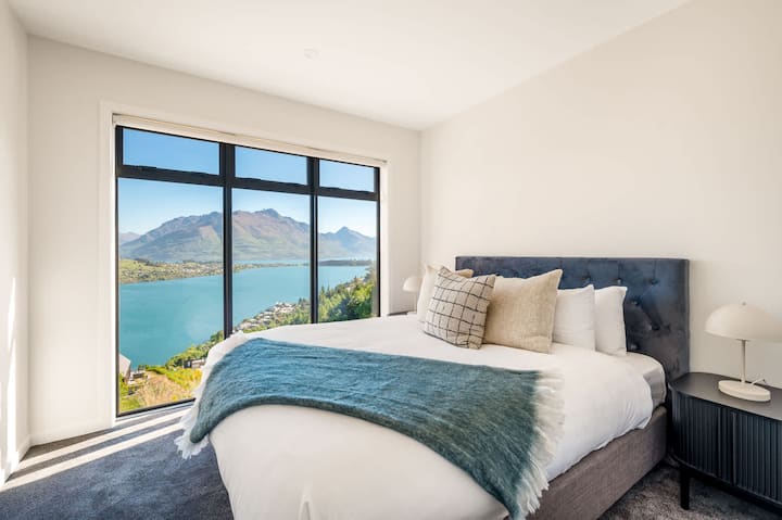 Tretia spálňa s malebným výhľadom a manželskou posteľou King – Táto útulná tretia spálňa má veľké okná s nádherným výhľadom na hory a jazero Queenstown spolu s flexibilnou rozdelenou posteľou King, ktorá ponúka pohodlie aj všestrannosť.