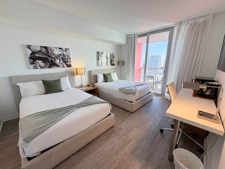 Ფართო საძინებელი ორი საწოლით, ბრტყელეკრანიანი ტელევიზორითა და კაშკაშა ბუნებრივი განათებით.