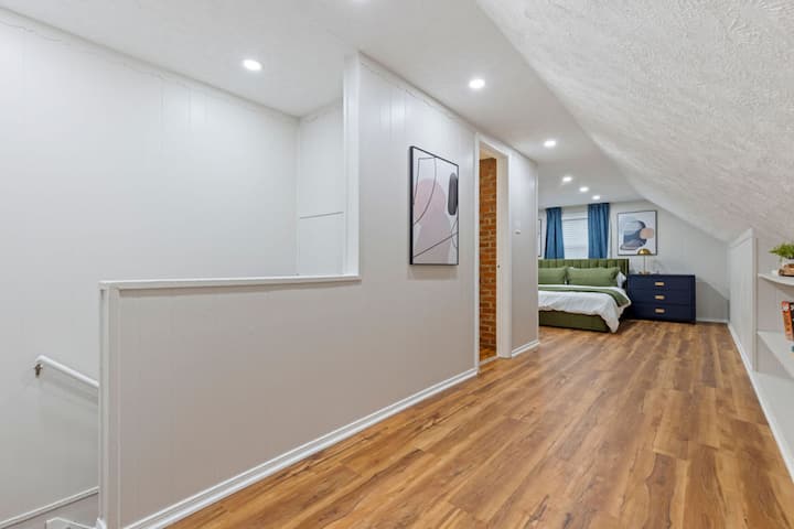 Teplá drevená podlaha a útulný priestor na spanie so štýlovou posteľou.