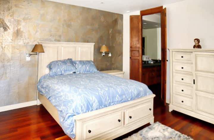 Habitación luminosa con cama tamaño king, tocadores de dos tonos y una pared decorativa con textura