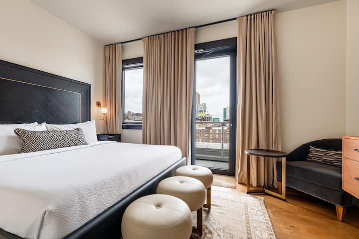 Quarto 2 - Cama king com guarda-roupa embutido, TV de tela plana e acesso direto ao pátio privado com vista para o centro da cidade.