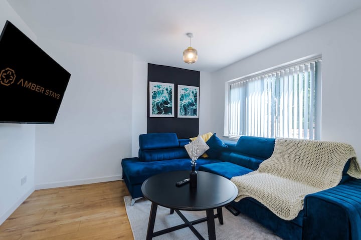 غرفة معيشة مشرقة وجذابة تتميز بأريكة مريحة وتلفزيون ذكي وديكور أنيق - مثالية للاسترخاء بعد يوم من الاستكشاف.