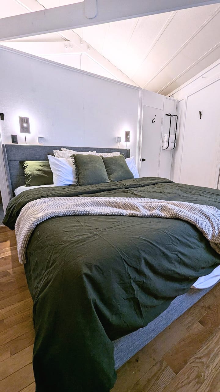 Pumzika kwa urahisi katika chumba hiki maridadi cha kulala chenye mwangaza maridadi wa ukuta, mito ya safu na matandiko ya kifahari kwa usiku wenye starehe mlimani.