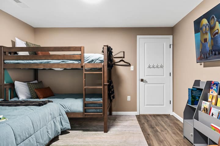 Deixe as crianças se divertirem neste quarto no porão com 4 camas de solteiro (3 visíveis e 1 cama de solteiro).