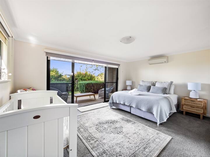 חדר השינה הידידותי למשפחות עם מיטת קווין סייז ועריסה לתינוק מציע גישה ישירה לגינות המטופחות להפליא