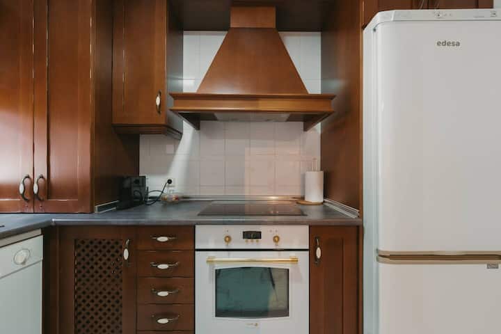 Cocina con campana extractora: vajilla completa, copas de vino y utensilios básicos.