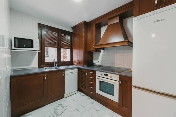 Cocina completa: horno, vitrocerámica, microondas, lavavajillas, nevera con congelador y lavadora.