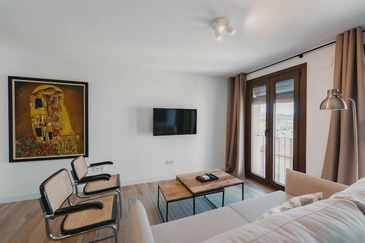 Salón con sofá cama, mesa de centro y TV.