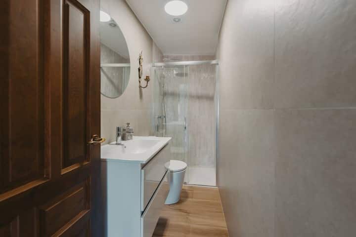 Baño completo con ducha de obra: toallas, champú y secador de pelo.