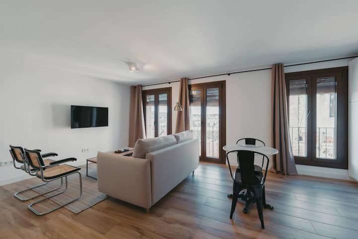 Salón con TV, balcones y zona de estar independiente.