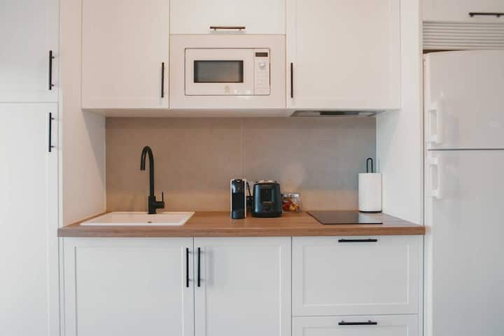 Cocina equipada: microondas, tostadora, vajilla completa y copas de vino.