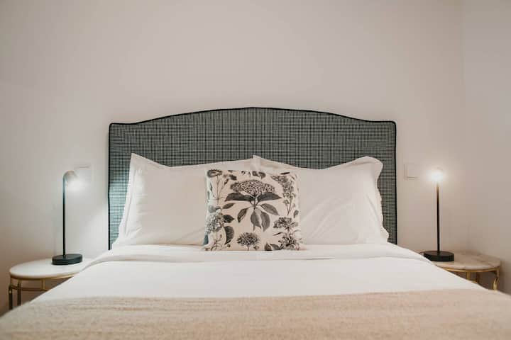 Dormitorio con cama de matrimonio y cortinas opacas.
