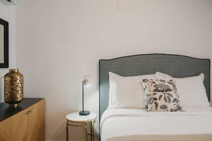 Dormitorio con lámparas de lectura y cabecero tapizado.