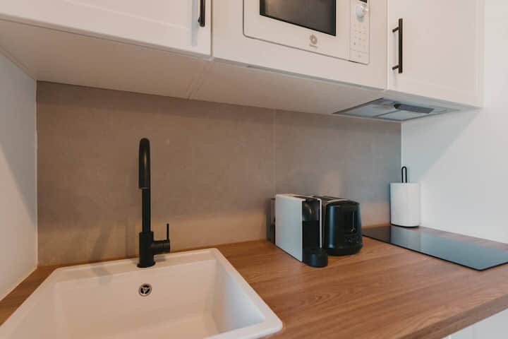 Cocina con cafetera, hervidor de agua y fregadero amplio.