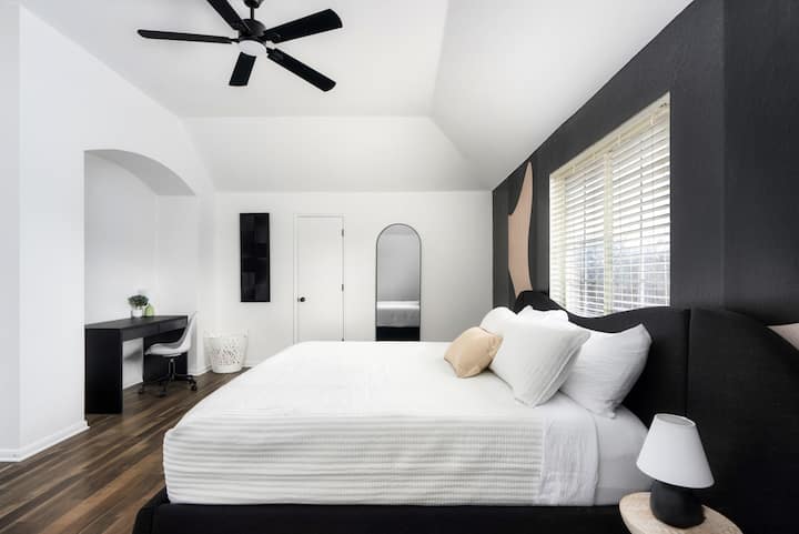 Relájate en este dormitorio elegante y moderno, con una lujosa cama tamaño king, una audaz pared de acento y un espacio de trabajo dedicado tanto a la relajación como a la productividad.