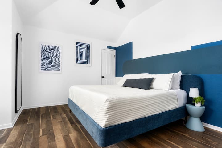 Relájate en este dormitorio moderno y sereno, con una lujosa cama, elegantes detalles azules y un ambiente relajante para el descanso nocturno perfecto.