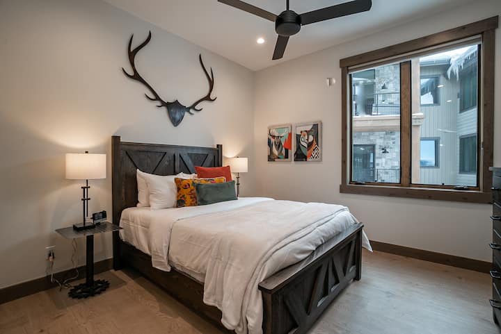 - საძინებლის მოწვევა სოფლის ხის საწოლის ჩარჩოთი და კედლის დეკორით
- ხრაშუნა თეთრი თეთრეული და ფერადი აქცენტის ბალიშები გულთბილ გარემოს ქმნის
- დიდ ფანჯრიდან იშლება ბუნებრივი სინათლე და შემოგარენის ხედები