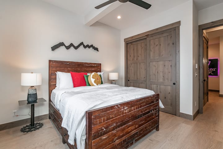 - მყუდრო საძინებელი სოფლის ხის საწოლის ჩარჩოთი და ფერადი აქცენტის ბალიშებით
- ორმაგი კარადის კარები გთავაზობთ საკმარის სათავსოებს გრძელი ვადით სტუმრობისთვის
- თბილი განათება და ნეიტრალური ტონები განტვირთვის საშუალებას იძლევა