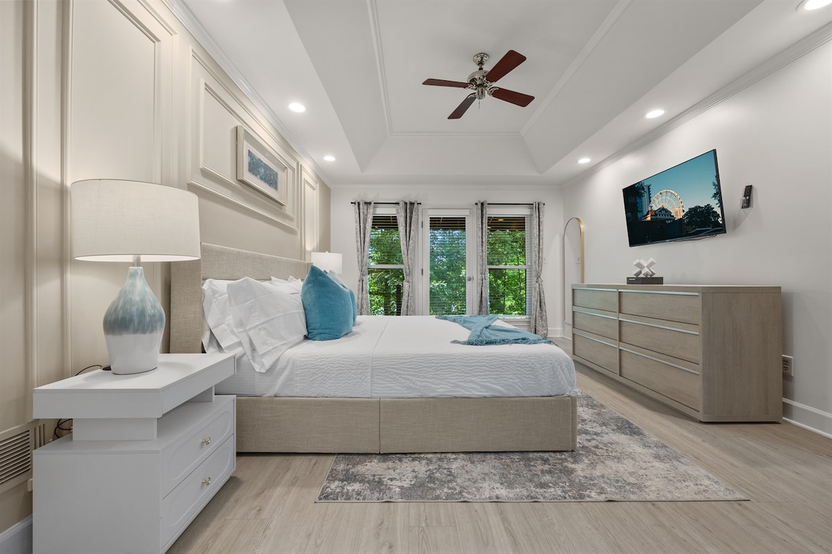 Chumba cha msingi chenye kitanda aina ya king, mashuka ya kifahari, televisheni mahiri na ufikiaji wa roshani ya kujitegemea unaoangalia miti.