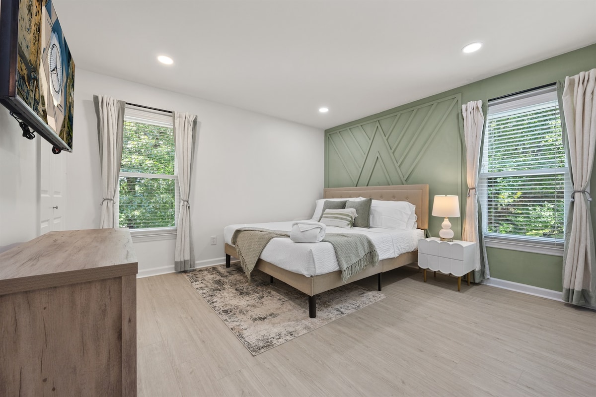 Ukuta wa lafudhi ya kijani kibichi unaongeza mguso wa kutuliza kwa chumba hiki cha kulala cha kifalme kilichowekwa vizuri, kinachofaa kwa usingizi wa usiku wenye utulivu.