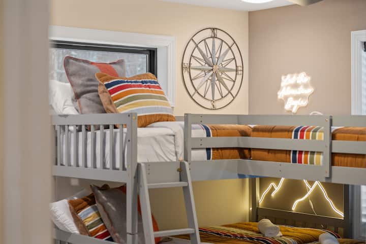 En la habitación de literas, la ropa de cama a rayas, un reloj de brújula y un letrero de neón juguetón traen un espíritu aventurero y apto para niños.