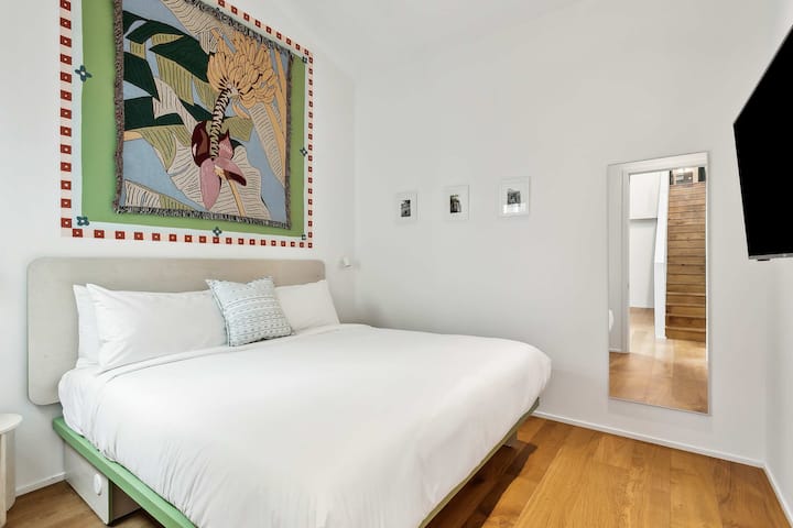 Bedroom 1: king bed, downstairs. Its en-suite bath also opens to the hall. Art: Banana Tree Blanket by We Might Be On Fire.