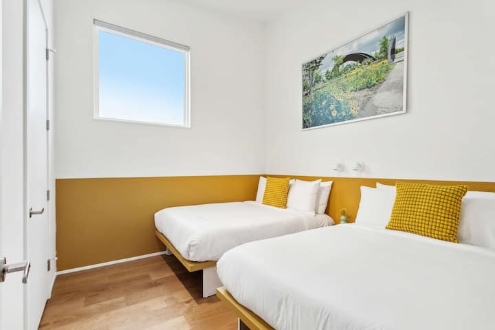 Bedroom 8: two full beds, upstairs. It shares a jack-and-jill bath with Bedroom 7. Art: Rusty Rainbow, Jim West's photo of the Piety Street Bridge.