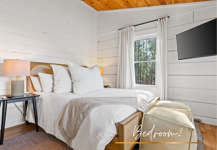 Cozy and inviting bedroom, featuring a queen-sized bed, natural wood accents, and serene forest views, perfect for a relaxing getaway.