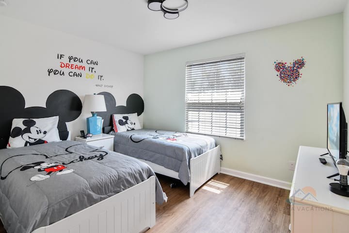 חדר שינה של מיקי מאוס עם 2 מיטות יחיד וטלוויזיה.