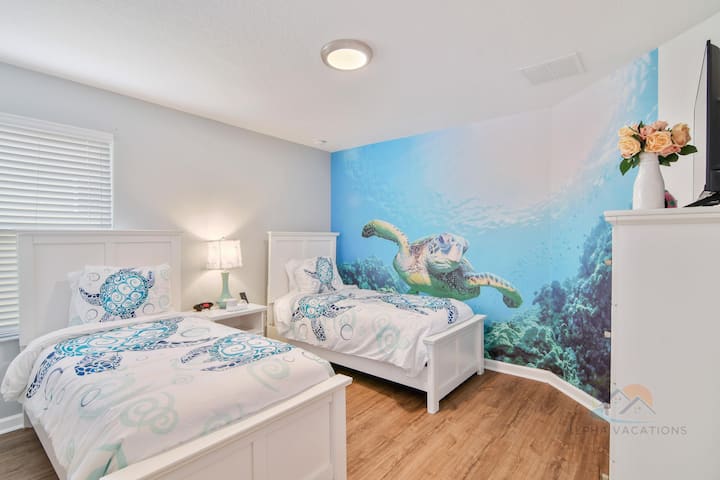 חדר שינה כפול מקסים עם עיצוב בסגנון ימי וציור קיר של צב ים.